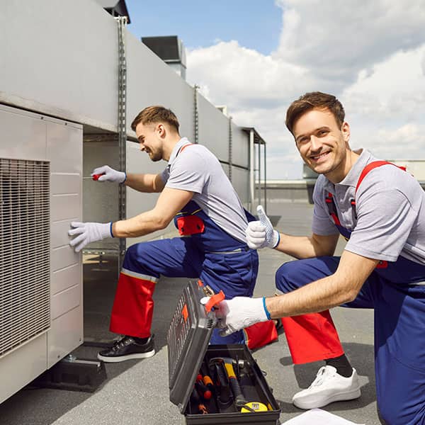 Two HVAC technicians working on an air conditioning unit