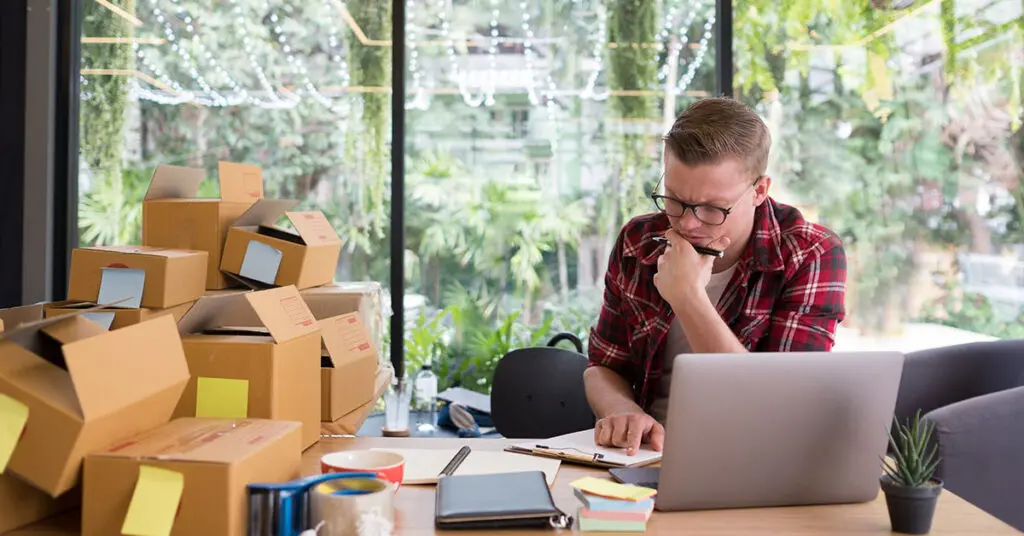Small business owner looking overwhelmed while managing marketing tasks alone on their laptop
