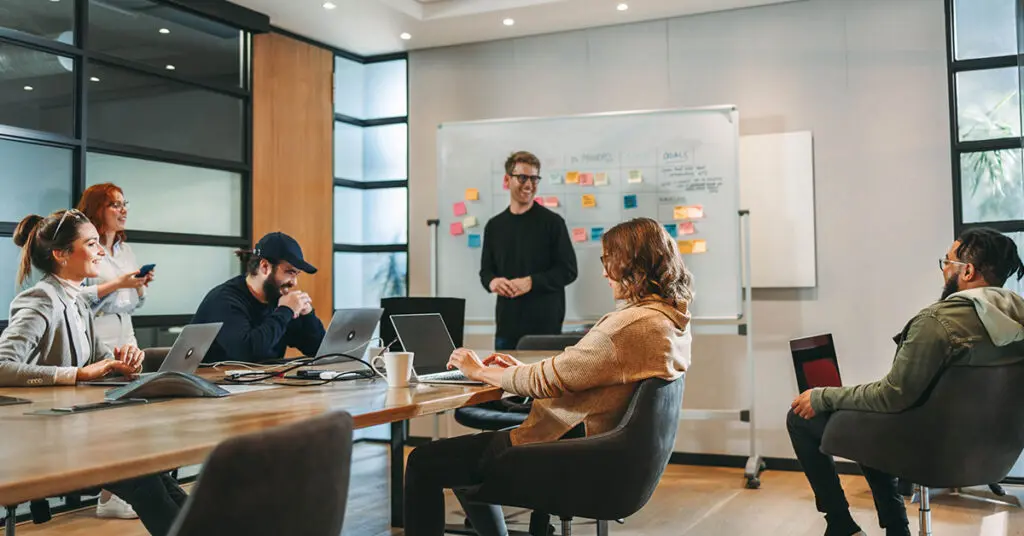 Creative team collaborating at a marketing agency with one remote contributor visible on a video call